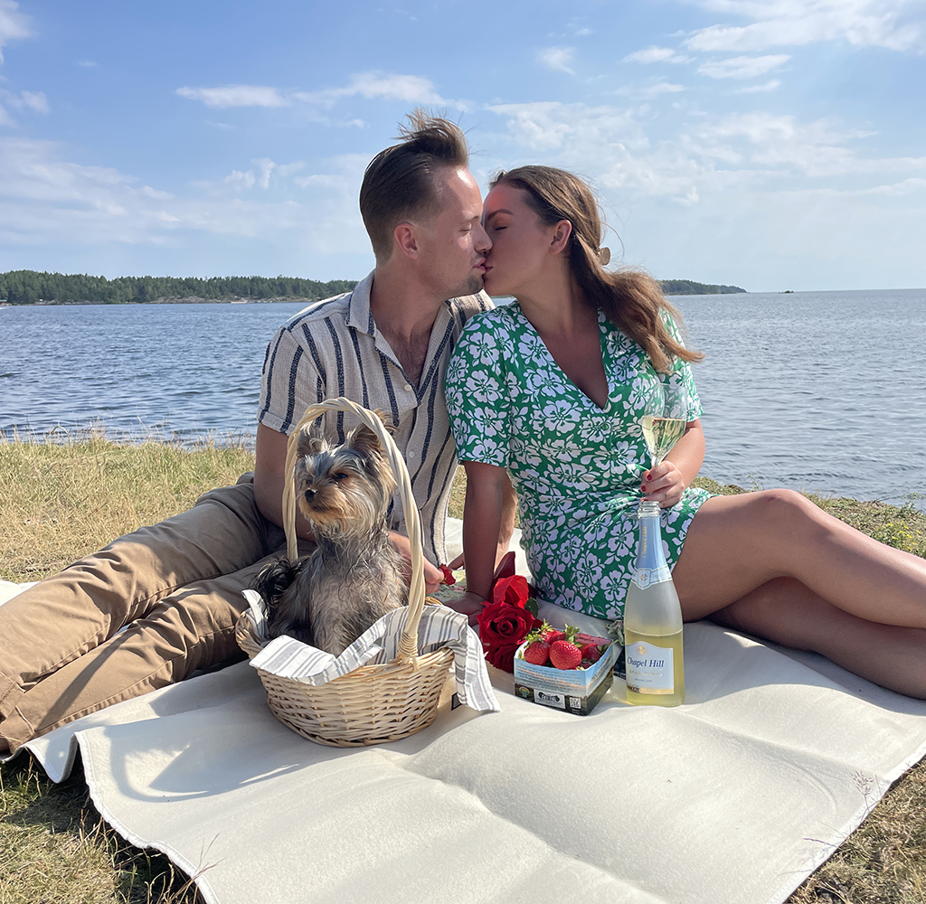 Amanda och Chris från Bonde söker fru sitter på en picnicfilt och pussas.